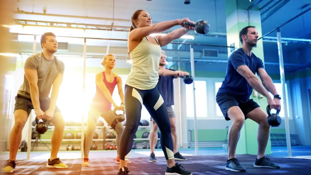 A group of fitness enthusiasts are exercising with dumbbells inside a gym