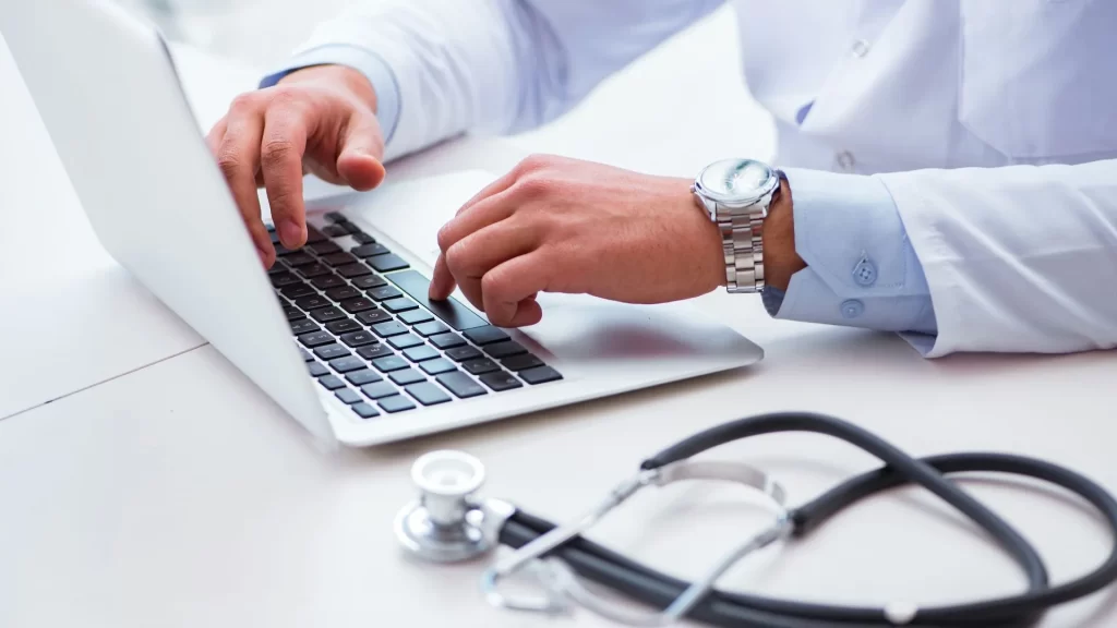 A doctor typing on a laptop