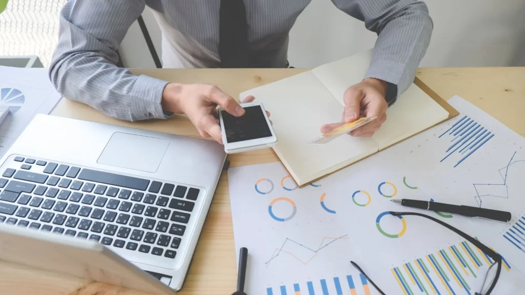 An office table showing hands of a professional studying graphs discussing customer retention while subscribing to a SAAS platform