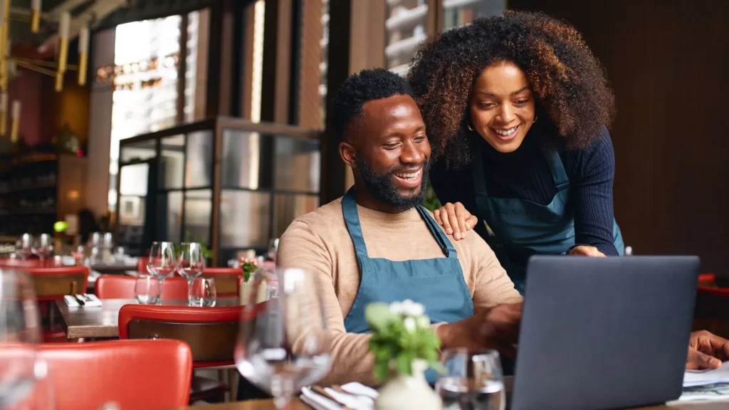 Business partners of a local business smiling at their laptop