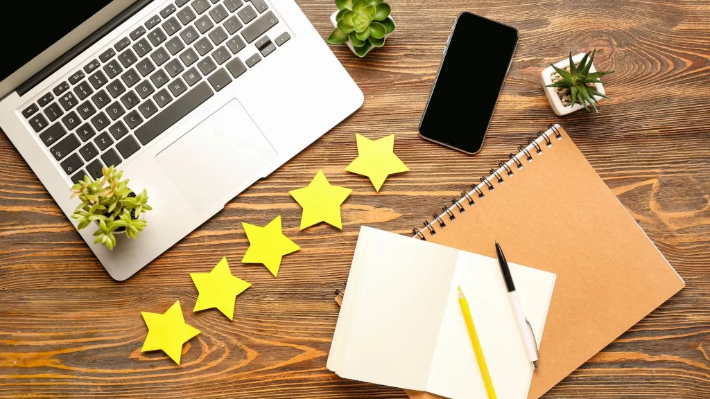 A laptop laid out in a table with some star cut outs representing google review removal services